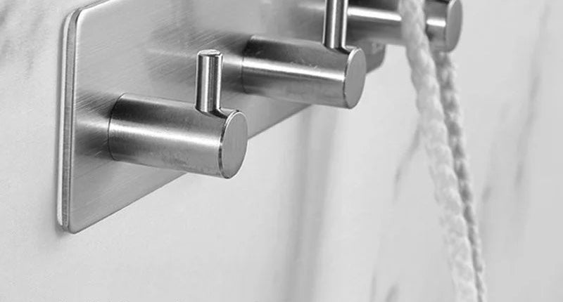 Brushed stainless no-drill adhesive hooks holding a rope bag on a tiled wall